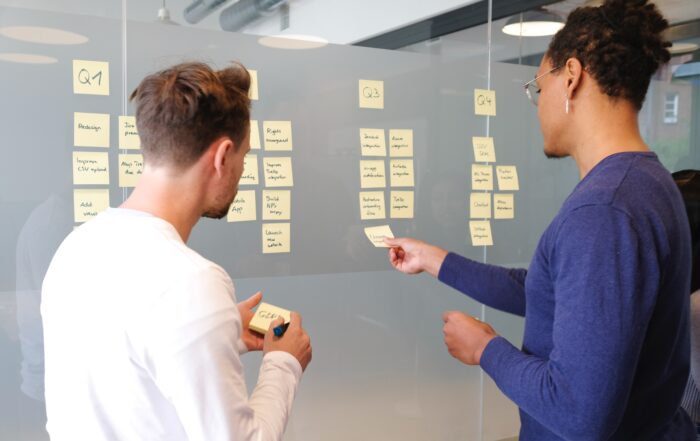 two people standing in front of a board with post it notes sharing thoughts to reflect a collaborative environment for marketing teams