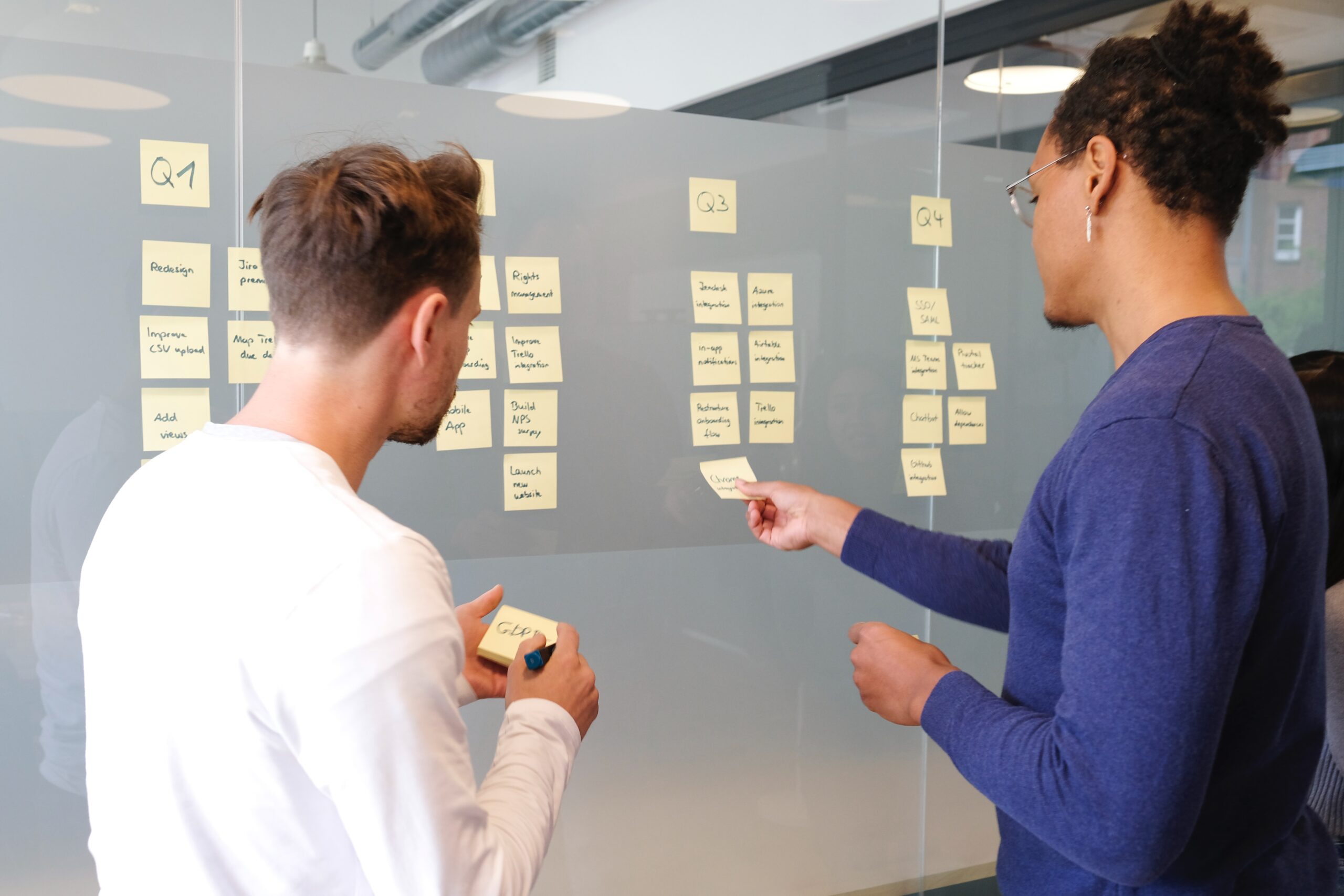 two people standing in front of a board with post it notes sharing thoughts to reflect a collaborative environment for marketing teams